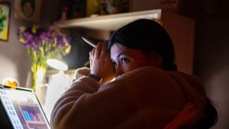 Person sits at a desk, looking thoughtfully at their laptop screen in a brightly lit room, representing the search for rel...