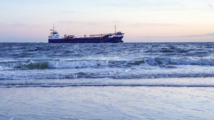 Small, agile speedboat cutting through the ocean waves, powerfully outmaneuvering a massive container ship in the backgrou...