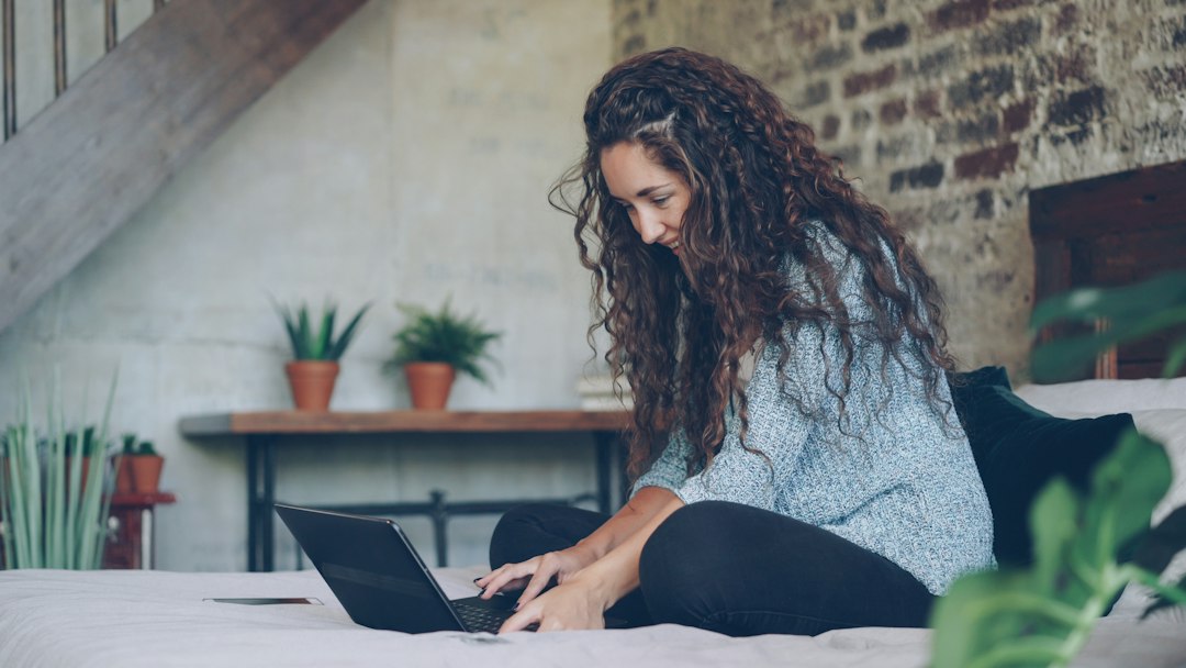 A woman sits at a clean, minimalist desk with a planner and laptop, strategically organizing her home move in a bright and calm environment.